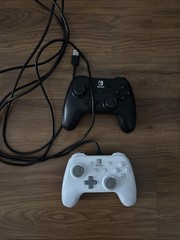 Two Black And White Nintendo Controllers With Cord